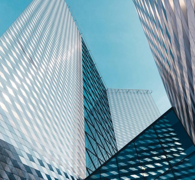 Futuristic skyscrapers in Vilnius with reflective geometric facades under a clear sky.